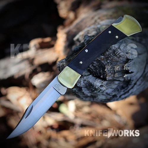 The Buck 110 Slim Heritage Elite 0110BRS19 is shown open, featuring a satin CPM MagnaCut clip point blade, lockback mechanism, and genuine ebony wood handle with brass bolsters and a deep-carry pocket clip.