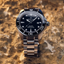 Reloj Certina DS Action Diver C032.607.11.051.00 con esfera negra y bisel cerámico sobre superficie de piedra