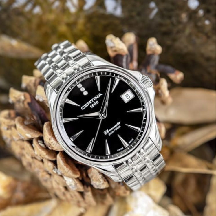 Reloj Certina DS Action Lady C032.051.11.056.00 con esfera negra y brazalete de acero sobre hojas secas