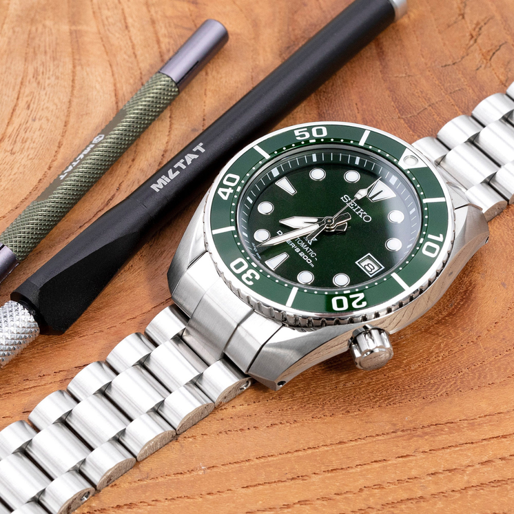 Reloj Seiko Prospex Diver's Sumo SPB103J1 con esfera verde y brazalete de acero sobre superficie de madera