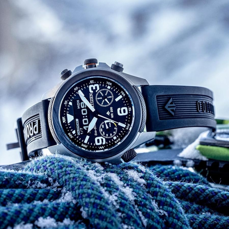 Reloj Citizen Eco Drive Land JV1007-07E con esfera gris y correa negra sobre fondo outdoor