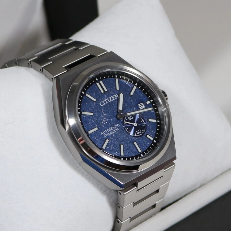 Reloj Citizen NJ0180-80L con esfera azul y brazalete de Super Titanium sobre superficie clara