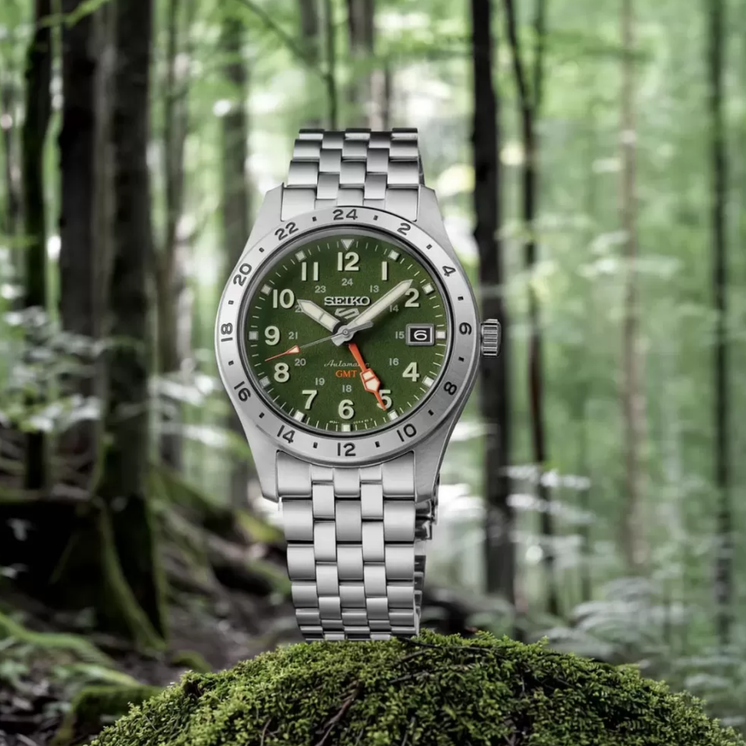 Seiko 5 Sports Field GMT HDB001K1 con esfera verde caqui y brazalete de acero inoxidable en fotografía lifestyle en el bosque