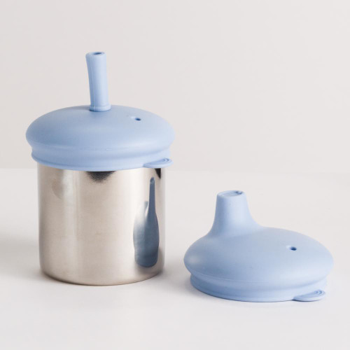 The Nestling Stainless Insulated Sip & Straw Cup in the Dusty Blue colour. The cup has the straw lid and straw attached with the sipper lid on it's own next to it.