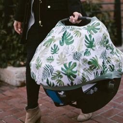 person carrying baby capsule with little unicorn muslin car seat canopy in tropical leaf design.jpg