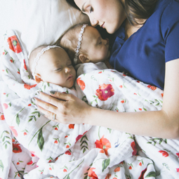 Two babies with mum cuddling under Little Unicorn Muslin Quilt.jpg