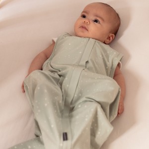 baby lying in cot wearing the sleep store 0.2 tog organic cotton sleeping bag in green star print
