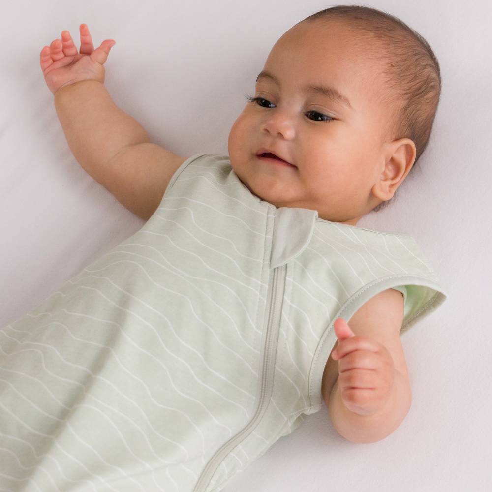 Baby with arms up wearing lightweight baby basics 0.2 tog sleeping bag for summer