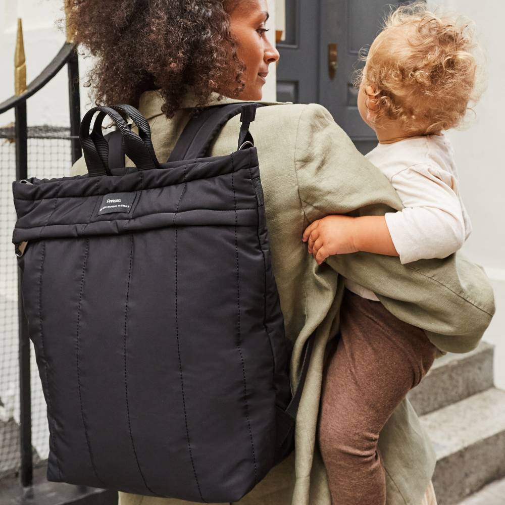 mum carrying baby and wearing the Finsson RAE eco changing backpack on her back