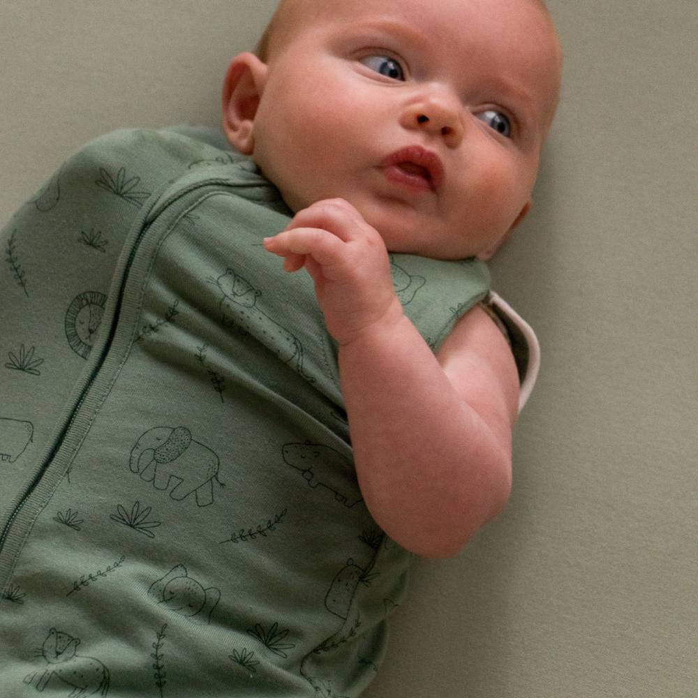 Baby swaddled with one arm out transitioning to sleeping bag in the sleep store 0.2 tog swaddle bag