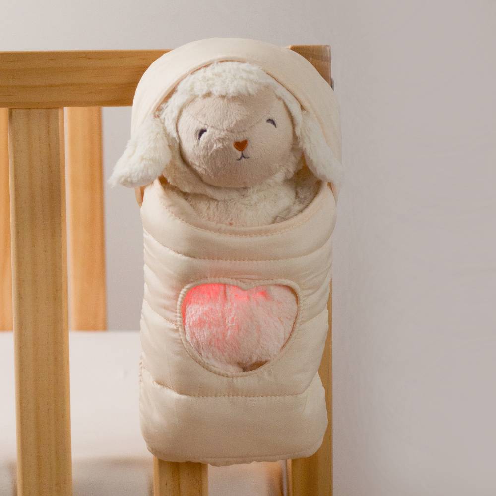 Loulou Lamb Glow Friend in it's sleeping bag hanging on a cot