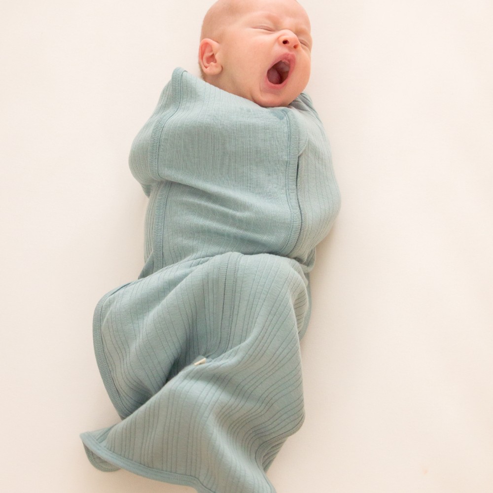 newborn baby yawning while swaddled in a woolbabe merino/organic cotton fitted  swaddle in Tide colour