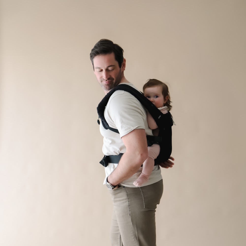 Dad looking at camera with baby on back in a Boba Auri Baby Carrier