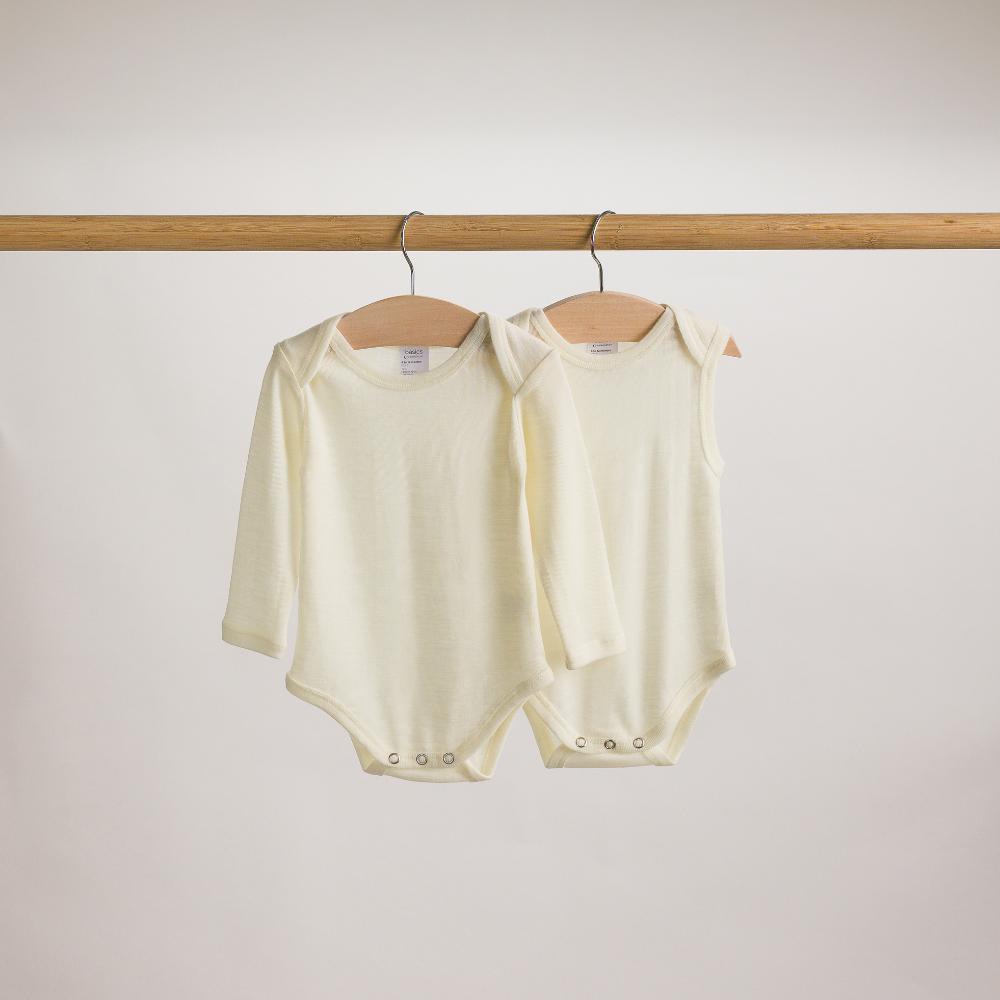 Hanging shot of The Sleeps Store's Basics Merino Singletsuit and Long Sleeve Bodysuit in the colour Cream.