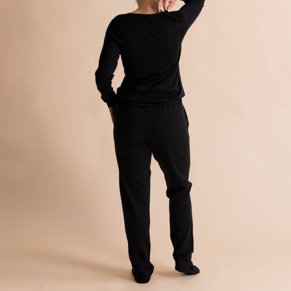 A reverse shot of a woman wearing The Sleep Store Merino Tencel Fleece Adult Joggers in Black.