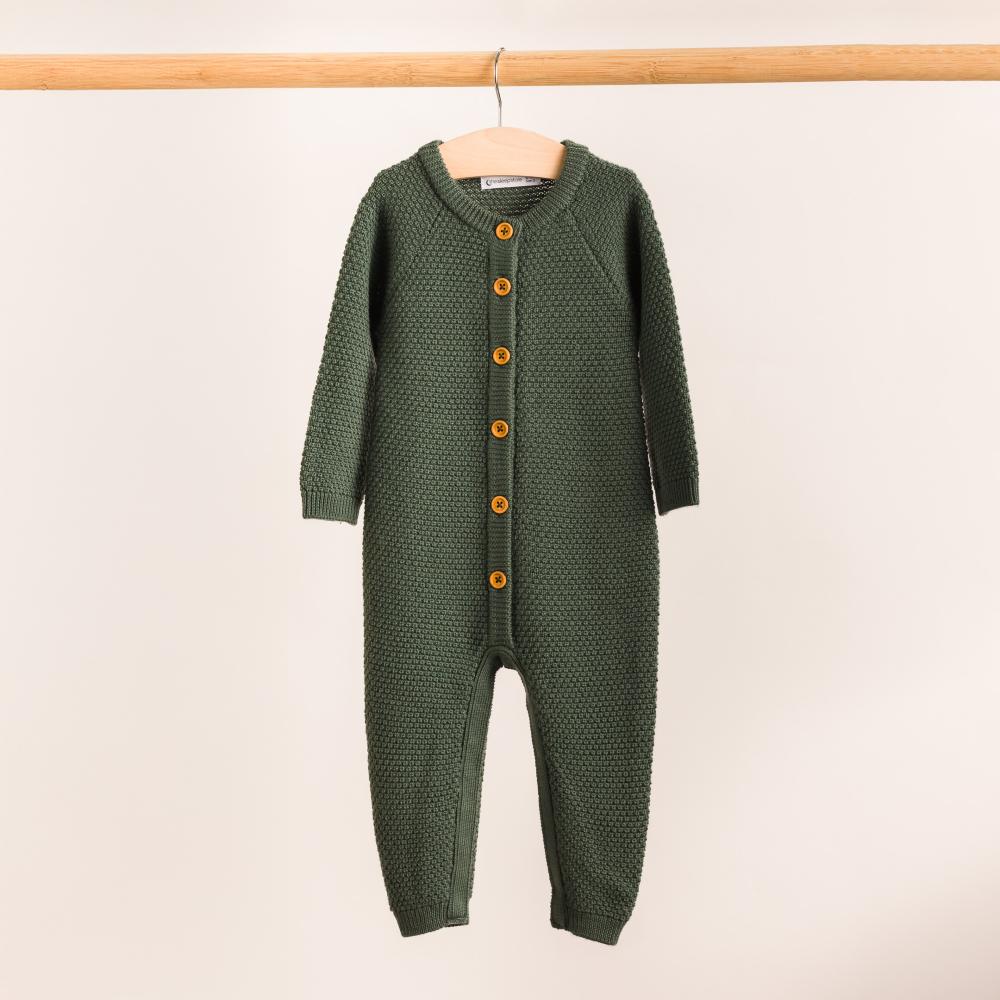The Sleep Store Merino Knit Onesie hanging on a wooden rack