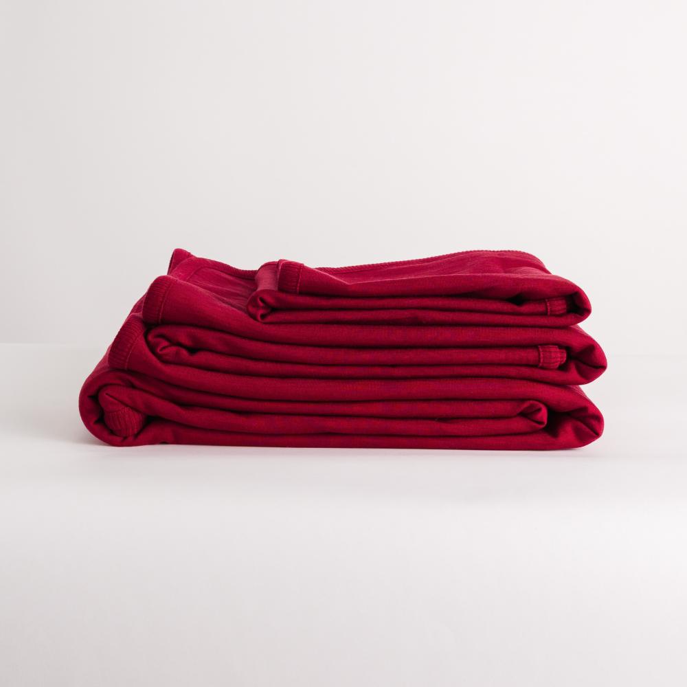 A side shot of The Sleep Store Merino Tencel Fleece Blankets in Berry, folded showing the different sizes - Bassinet, Cot and Throw.