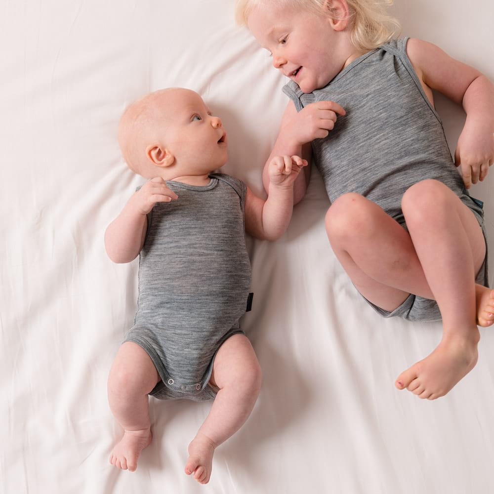 Baby and toddler looking at each other both wearing grey The Sleep Store Deluxe Merino Rib Singletsuits