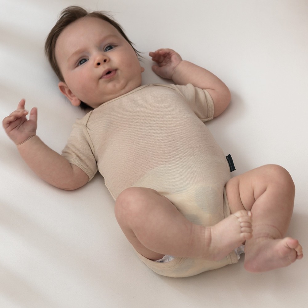 4 month old baby wearing The Sleep Store deluxe merino rib short-sleeve bodysuit in Almond