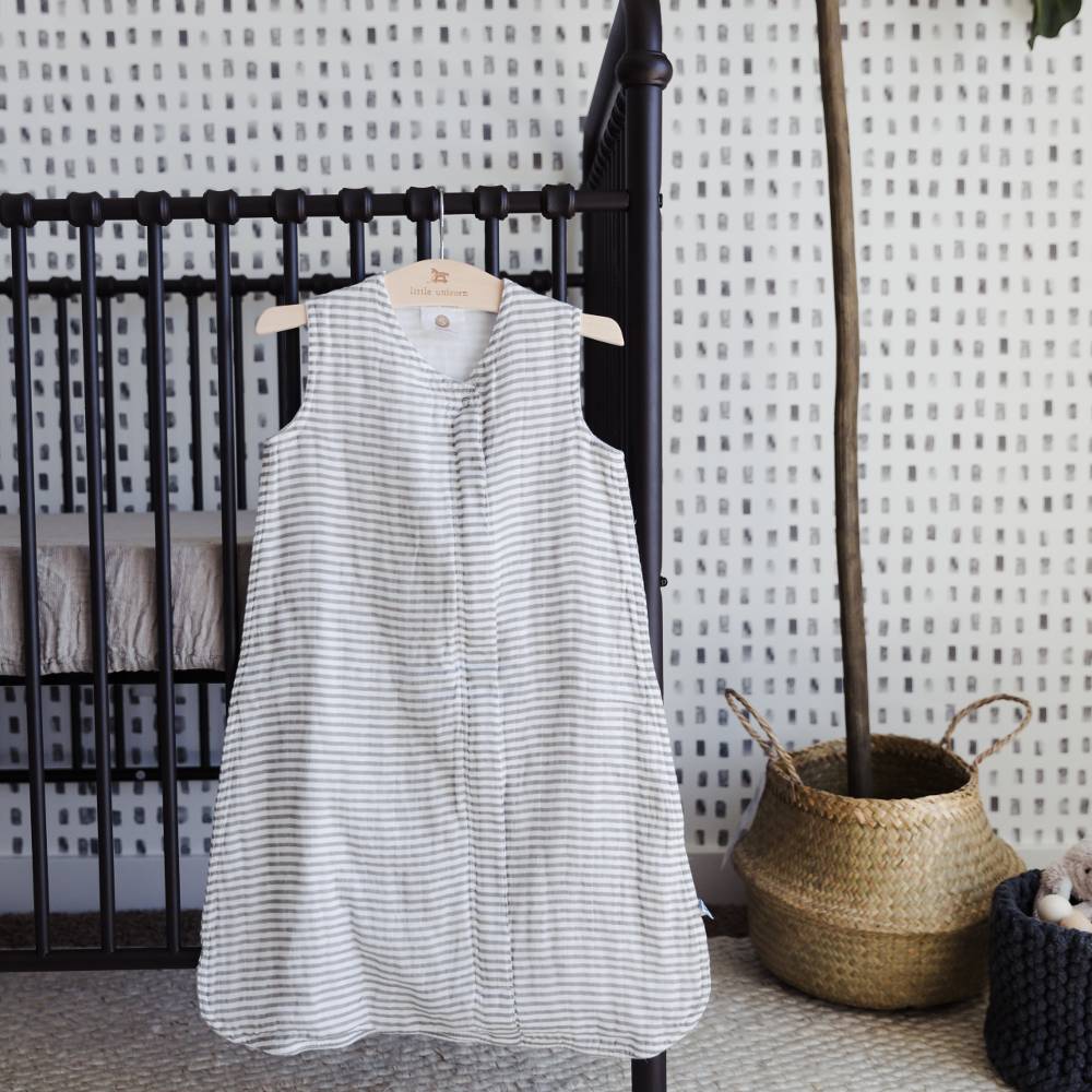 Nursery with Little Unicorn 1.0 Tog rated cotton muslin sleeping bag hanging on the cot bars