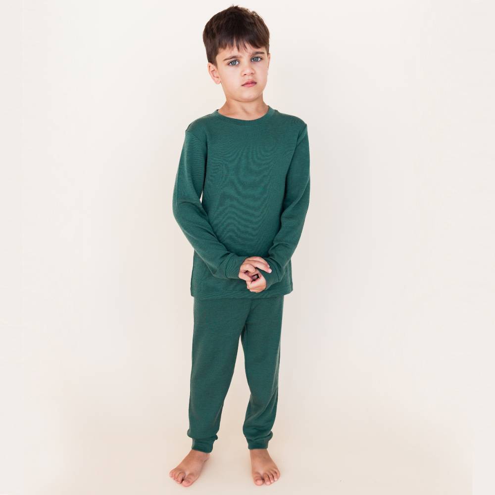 School aged boy wearing The Sleep Store Deluxe Merino Rib Pyjamas in Evergreen