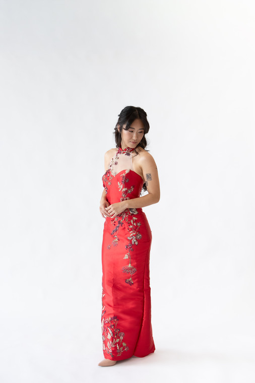 Halter neck red cheongsam gown featuring elegant floral embroidery and asymmetrical neckline. Perfect for tea ceremonies or modern cultural weddings. Available to purchase or hire at Bridal Fusion by Steph in Auckland. Under $2,000, with over 10+ styles to try on.