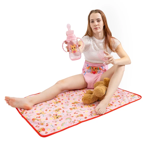 Female model sitting on change pad with stuffed animal and pink easy grip bottle.