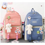 Cute girl travel bags, pink and blue waterproof backpacks with teddy bear keychains and colorful stickers.