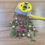 Dollhouse Miniature Garden Scene with pink and magenta flowers, green vines on a wooden surface.
