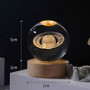 Common Good 5cm Crystal Ball Lamp with glowing Saturn and planets on wooden base.