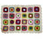 Handmade crochet daisy blanket with colorful floral granny squares on a white background with scalloped edges.