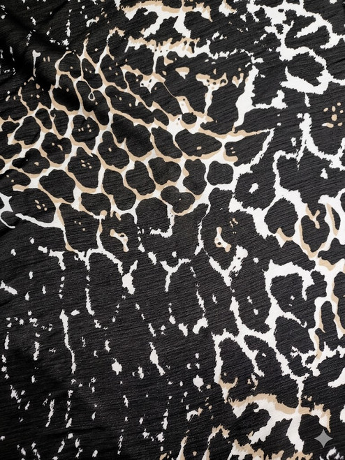 Textured animal print Yoryu chiffon crinkle fabric in black and neutral tones, showcasing the characteristic vertical ridges and lightweight drape for textile retail.