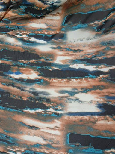 Top-down close-up of 100% polyester Chiffon fabric showing detailed abstract marble print with electric blue and copper accents.