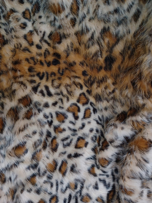 plush leopard-print faux fur fabric. The pattern features organic, irregular black rosettes and spots scattered across a background that gradients from deep amber and tawny gold to soft cream and off-white