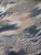close-up of 100% polyester chiffon fabric featuring a sophisticated watercolor abstract animal print. The design blends soft zebra stripes and cheetah patterns in a palette of slate blue, sandy beige, and charcoal grey, creating a "washed" artistic effect.