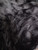 black polyester fabric consisting of a sheer mesh base heavily decorated with thick, shaggy clumps of black tinsel.
