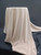 Cream-colored, plush, faux-velvet, minky-style fleece fabric draped over a stand against a dark grey backdrop, ideal for luxury throws, blankets, and crafts.