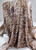 Side profile of flowing animal print ITY polyester fabric, showcasing a fluid drape and abstract tiger stripe pattern in earth tones for apparel sewing.