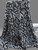 A professional studio shot of draped Rayon Challis fabric featuring a bold, black abstract graffiti pattern. The textile is displayed against a clean, neutral gray background, showcasing its fluid drape and soft, lightweight texture. The base of the fabric has a sophisticated, slight blue-silver tinge, providing a modern contrast to the deep black urban print.