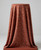 Terracotta Ditsy Floral Rayon Challis fabric with a delicate cream and blue mini flower print, draped smoothly over a pedestal against a clean neutral gray studio background to showcase its soft, fluid drape.
