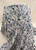 Watercolor botanical floral rayon challis fabric draped over a pedestal stand against a neutral cream background, highlighting the soft fabric folds, fluid drape, and slate blue print.