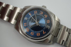 A fine Rolex Air King reference 114200 in stainless steel, dated 2010. This particular sports model is striking for its vivid blue concentric dial and pop of orange hour markers with white accents, a nod to the New York Mets. It appears to be in unworn condition as it has full stickers so we consider this to be a safe queen. Great opportunity to own one in such incredible condition.  Modeled on size 6 inch wrist.

Original dial, hands and crown.
Case measures 35 x 42mm, 12mm thick.
Serial# M4723xx
Rolex steel bracelet contains 12.5 links (full size).
19mm lug width.
Rolex inner and outer green box.
Rolex card and papers.