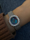 A fine vintage Audemars Piguet opal and diamond bracelet watch in 18k white gold, crafted during the 1980s. A stunning oval accessory for the fiery gem quality opal dial Audemars is renowned in selecting for their fine pieces, surrounded by round brilliant cut diamonds. Both the opal and diamonds catch the light in a way that refracts a glitter of rainbow colors. This piece will dazzle the wearer and suit a variety of occasions, its interlinked chain bracelet wearing comfortably on the wrist. Modeled on 6 inch wrist.

The opal has faint crack at 4 o’clock position that is imperceptible with the naked eye due to the competing opal. Light scratch on center crystal. 
Factory round cut .10 carat diamond set bezel; 2 carats total approximate.
Original opal dial, hands and crown. 
Case measures 21.5 x 22.5 mm, 6.5 mm thick. 
AP cal. 2430, 18 jewel backwind set movement. 
Case# 194xx Movement# 2636xx
Sapphire crystal. 
AP signed bracelet, measures and fits 6 3/4 inches or 17cm approximate, 12mm wide.