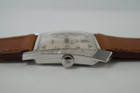 A vintage LeCoultre Asymmetrical reference 2406 in 14k white gold, crafted circa 1950. The curiously shaped case measures 28 mm across and tapers to 23 mm with a 9 mm thickness due the domed glass crystal. The bezel contains finely hatched texture and houses a silvered dial with diamond hour markers, silver sword-shaped hands, subsidiary dial and a short crown stamped JL. Rare to find this timepiece in unpolished and beautiful condition, would made an excellent addition to a vintage lover’s collection.
