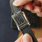 A late 1990s Cartier Tank Basculante in stainless steel, wonderfully constructed in a compact 22mm size. The dark grey patterned dial is contrasted by bright white stylized Arabic numerals and silvered sword-shaped hands, giving the watch a distinctive monochromatic look.
The Basculante's hinged case is the highlight of the design, allowing the watch head to pivot within its frame and turn completely over. It opens and closes smoothly and can remain upright within the frame. A blue cabochon accents the case, while the crown is cleverly concealed and accessed only when the watch is flipped from its usual position.
Powered by a quartz movement and fitted with a custom dark grey Babele leather strap secured by a Cartier stainless steel deployant clasp. An unusual interpretation of the Tank, with much of its appeal found in the ingenious case construction.

Watch Details
Reference: 2386
Case Number: 3514xxxx
Case: Stainless steel
Case Size: 22 × 32 mm; 6 mm thick
Dial: Dark grey patterned dial; white Arabic numerals
Movement: Quartz
Crystal: Sapphire
Strap: Custom dark grey Babele leather, adjustable
Lug Width: 17 mm
Clasp: Cartier stainless steel deployant
Wrist Size: Fits up to approximately 6 1/2 inches
Modelled On: 6-inch wrist
Condition: Light wear shown
Service: New battery installed
