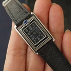 A late 1990s Cartier Tank Basculante in stainless steel, wonderfully constructed in a compact 22mm size. The dark grey patterned dial is contrasted by bright white stylized Arabic numerals and silvered sword-shaped hands, giving the watch a distinctive monochromatic look.
The Basculante's hinged case is the highlight of the design, allowing the watch head to pivot within its frame and turn completely over. It opens and closes smoothly and can remain upright within the frame. A blue cabochon accents the case, while the crown is cleverly concealed and accessed only when the watch is flipped from its usual position.
Powered by a quartz movement and fitted with a custom dark grey Babele leather strap secured by a Cartier stainless steel deployant clasp. An unusual interpretation of the Tank, with much of its appeal found in the ingenious case construction.

Watch Details
Reference: 2386
Case Number: 3514xxxx
Case: Stainless steel
Case Size: 22 × 32 mm; 6 mm thick
Dial: Dark grey patterned dial; white Arabic numerals
Movement: Quartz
Crystal: Sapphire
Strap: Custom dark grey Babele leather, adjustable
Lug Width: 17 mm
Clasp: Cartier stainless steel deployant
Wrist Size: Fits up to approximately 6 1/2 inches
Modelled On: 6-inch wrist
Condition: Light wear shown
Service: New battery installed