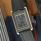 A late 1990s Cartier Tank Basculante in stainless steel, wonderfully constructed in a compact 22mm size. The dark grey patterned dial is contrasted by bright white stylized Arabic numerals and silvered sword-shaped hands, giving the watch a distinctive monochromatic look.
The Basculante's hinged case is the highlight of the design, allowing the watch head to pivot within its frame and turn completely over. It opens and closes smoothly and can remain upright within the frame. A blue cabochon accents the case, while the crown is cleverly concealed and accessed only when the watch is flipped from its usual position.
Powered by a quartz movement and fitted with a custom dark grey Babele leather strap secured by a Cartier stainless steel deployant clasp. An unusual interpretation of the Tank, with much of its appeal found in the ingenious case construction.

Watch Details
Reference: 2386
Case Number: 3514xxxx
Case: Stainless steel
Case Size: 22 × 32 mm; 6 mm thick
Dial: Dark grey patterned dial; white Arabic numerals
Movement: Quartz
Crystal: Sapphire
Strap: Custom dark grey Babele leather, adjustable
Lug Width: 17 mm
Clasp: Cartier stainless steel deployant
Wrist Size: Fits up to approximately 6 1/2 inches
Modelled On: 6-inch wrist
Condition: Light wear shown
Service: New battery installed