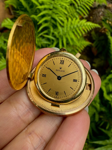 A fine vintage Rolex Liberty coin watch reference 3612 in 18k yellow gold, crafted in the early 1960s from a $20 US coin dated 1907. This piece feels lovely in the hand, impressively containing a mechanical movement in its 4mm case. A clever opening mechanism holding a near-seamless button positioned at 3 o’clock, delicately releases its lid. The watch may be propped up on its own by lifting the small lever located at 12 o’clock, and features a champagne dial, blued steel hands, black Roman numeral and stick hour markers with a minute track. With such exquisite craftsmanship, this piece would make a luxurious addition to a collection or as decor. 

Scratches and small nicks throughout.
Watch runs and winds smoothly, it will need a service. Service history is unknown. 
Original dial, hands and crown.
Case measures 34.5mm, 4mm thick. 
Rolex cal. Agassiz, 18 Rubis mechanical winding. 
Acrylic crystal.
Serial# 689715