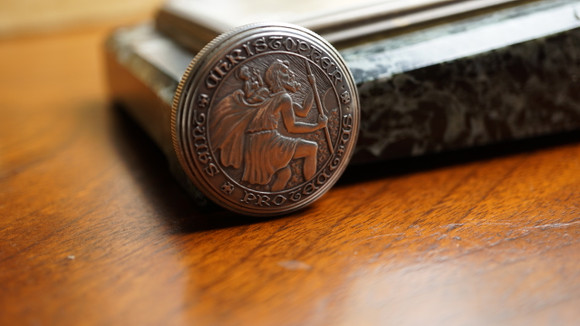 A fine vintage Movado St. Christopher coin watch in sterling silver, crafted circa 1950-60s. Designed as a coin measuring 32mm and 9mm thick with St. Christopher motif on either side of the watch and ridging around the edges. Depressing the hidden mechanism located on the edge of the coin at 3 o’clock opens the watch, of which can be lifted through a small lip. A crown sits atop of 12 o’clock, the silvered dial contains silver diamond and Arabic hour markers, outer silver beaded minute track, and dauphine hands. Lavishly designed on the outside while maintaining simplicity in the interior.
