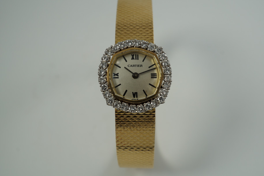 A very nice vintage Movado bracelet watch in 18k yellow gold, crafted during the late 1960s. Once retailed by Cartier, the subtle hexagonal polished case with original finish is surrounded by 28 diamonds weighing 1.12 carat total weight, houses a silver dial signed Cartier with black stick and Roman numerals and stick hands. Resembling a floral design further accentuated by a beautifully crafted integrated bracelet with a backwind function that adds to its daintiness. Suitable for casual and dressy occasions.